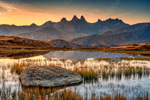 Sunrise shines over Lac Guichard with Arves massif and lake reflection in autumn at Aiguilles d'Arves, French Alps, France