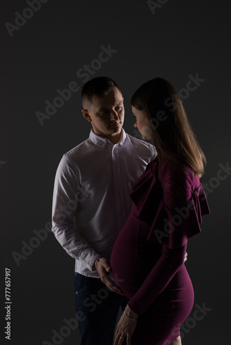 portrait of a couple, pregnant couple on a black background close up, fashion pregnant model, pregnant woman stands on a black background, studio pregnancy photo shoot