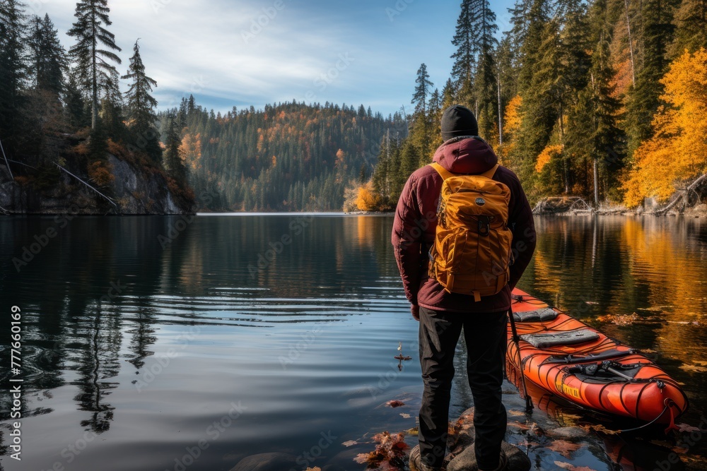A man stands beside a kayak on a tranquil lake
