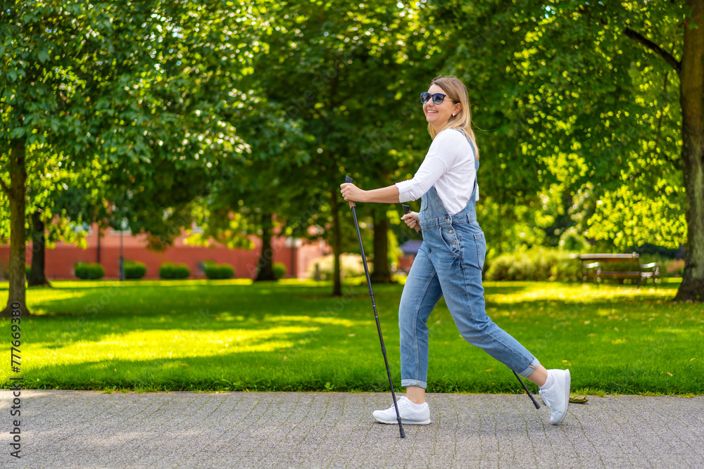 Fototapeta premium Nordic walking - woman exercising in city park 