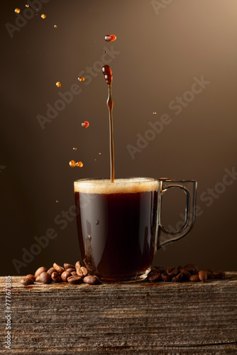 Espresso coffee glass cup with splashes on a brown background. © Igor Normann
