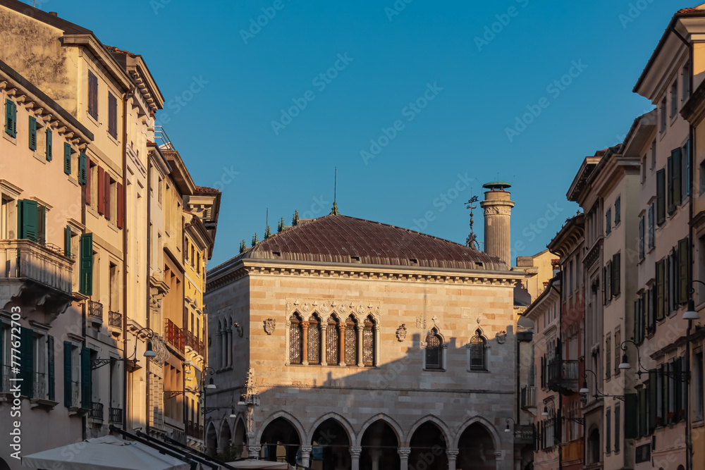 Stroll along narrow urban street at sunrise that meanders towards magnificent ancient city center of charming town Udine, Friuli Venezia Giulia, Italy, Europe. Urban tourism in northern Italian city