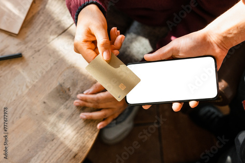 The woman puts the card to the phone for payment photo