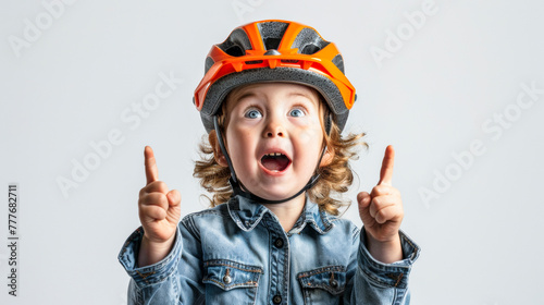 Excited Child Cyclist. Surprised boy in yellow shirt and helmet pointing upwards.