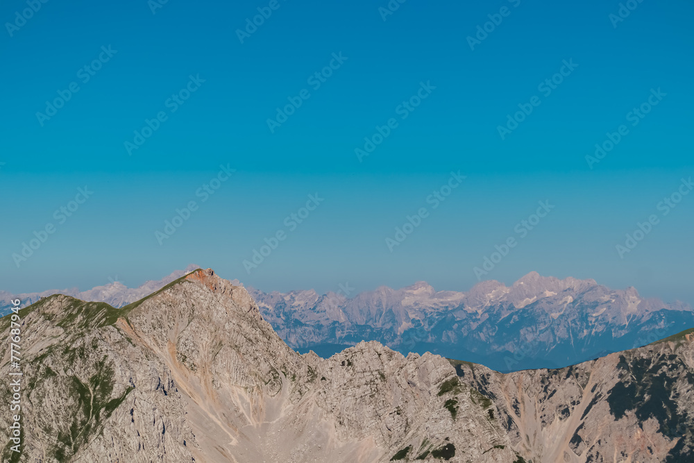 Scenic view of majestic mountain peak Hochstuhl (Stol) in untamed Karawanks, border Slovenia Austria. Looking from Vertatscha peak. Hiking wanderlust in wilderness of Slovenian Alps in summer