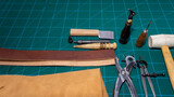 Work table. Leathercraft in workshop with specific leather work tools, on cutting board. to build a belt