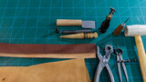 Work table. Leathercraft in workshop with specific leather work tools, on cutting board. to build a belt