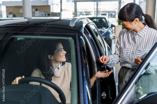 Female executive giving keys to happy new car owner 