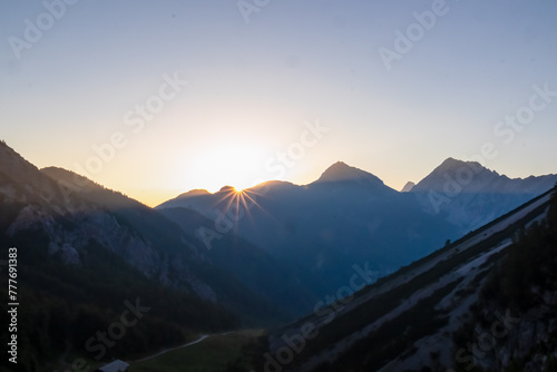 Panorama of stunning sunrise with golden sun beams over majestic summits of untamed Karawanks mountain range. Vantage point of Loibl Pass, border Austria Slovenia. First rays of morning sun in Alps photo