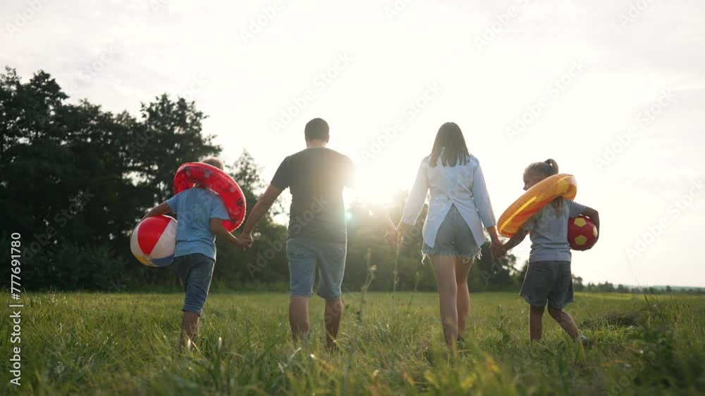 Family day. parents with children at sunset with balls in life preservers. family walk in park with balls on family day. children in life preservers with balls and parents taking walk together in park Family day. parents with children at sunset with balls in life preservers. family walk in park with balls on family day. children in life preservers with balls and parents taking walk together in park