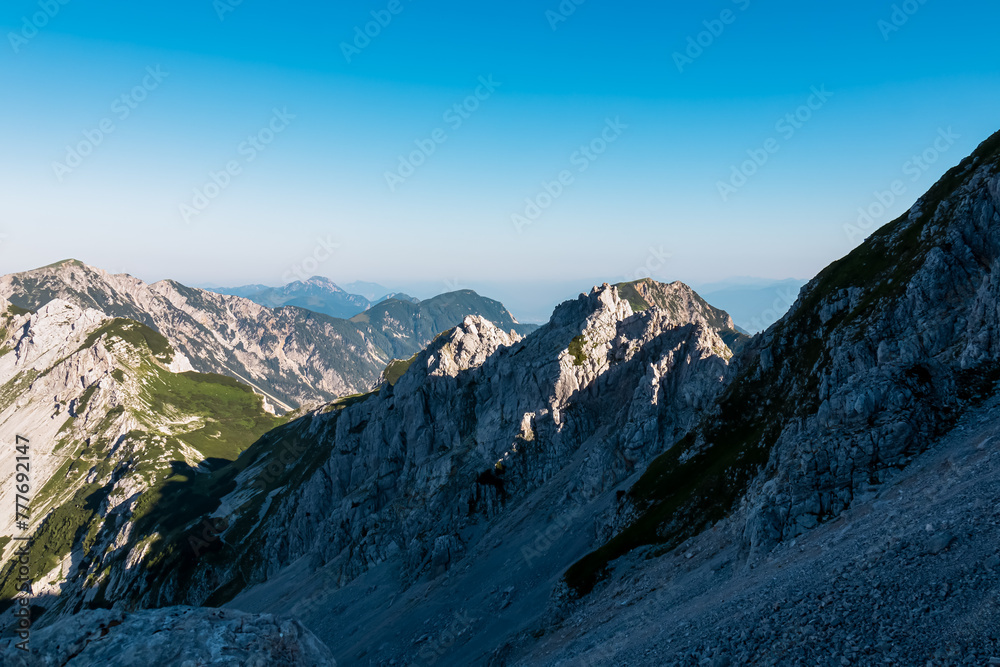 Panoramic view of majestic mountain peaks untamed Karawanks and Julian Alps, border Slovenia Austria. Hiking trail from Loibl Pass to Vertatscha. Wanderlust in wilderness of Slovenian Alps in summer