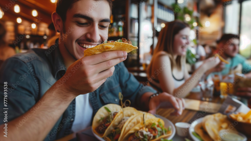 Young man enjoying in taste of tacos while having lunch with friends in restaurant.
Young man enjoying in taste of tacos while having lunch with friends in restaurant.