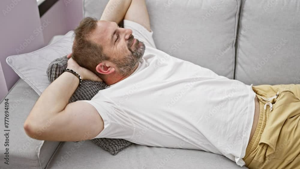 Relaxed middle-aged man with beard lying on a sofa in a cozy home interior, embodying tranquility and comfort. Relaxed middle-aged man with beard lying on a sofa in a cozy home interior, embodying tranquility and comfort.