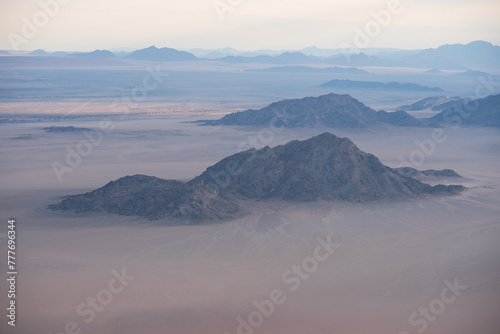Breathtaking sunrise over the sand dunes of Sossusvlei, Namibia, captured from a helicopter. The first light of dawn casts dramatic shadows and highlights the vibrant colors of the desert.