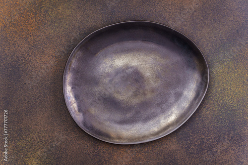 Empty black irregular plate on concrete background. Top view, with copy space