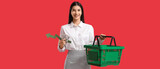 Young woman with shopping basket, money and arrow on red background. Price rise concept