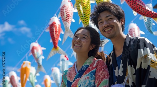 Happy Japanese couple in kimono with koi fish on blue sky background. Concept of Celebrate Golden Week in Japan or National Koi Day. Children’s Day in Japan. Kodomo no Hi photo