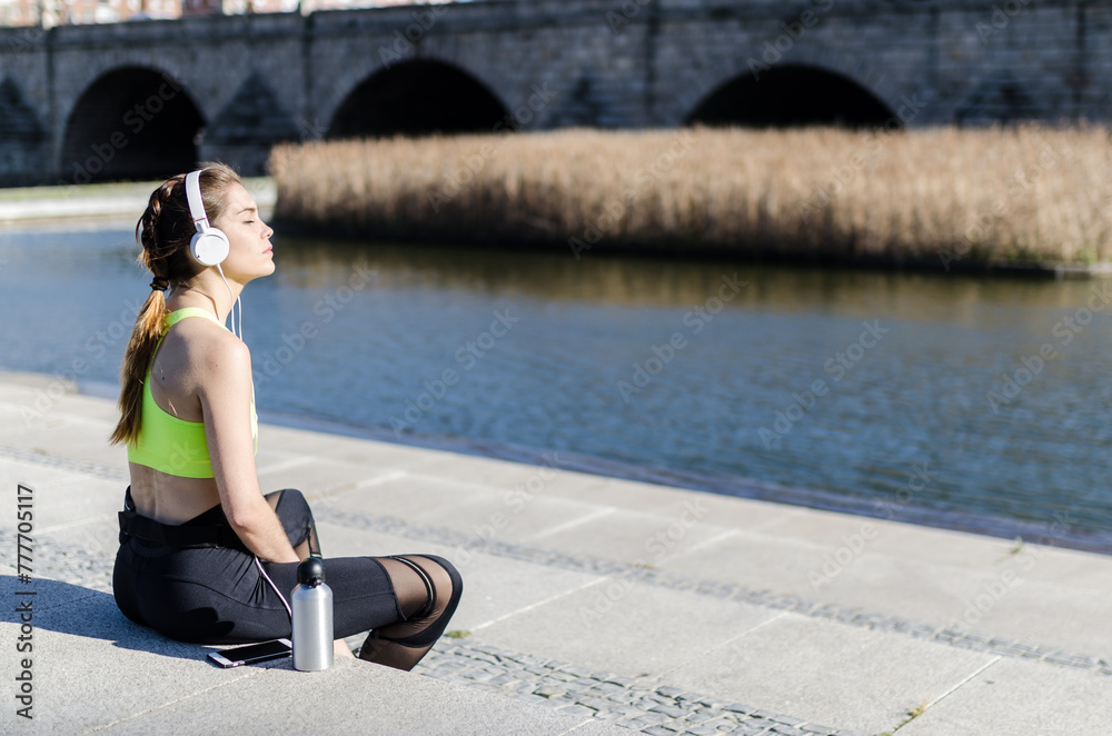 healthy woman resting and listening music with mobile phone while doing yoga and workout