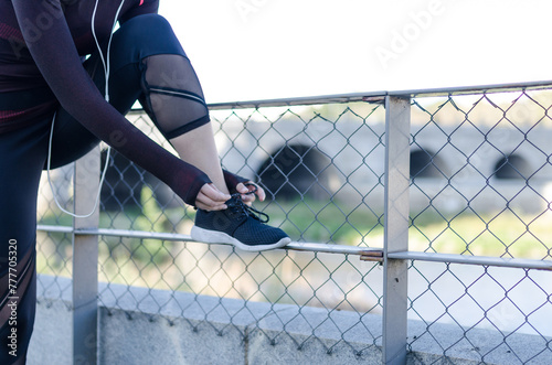 woman tying shoelaces while running outdoor and listening music with headphones