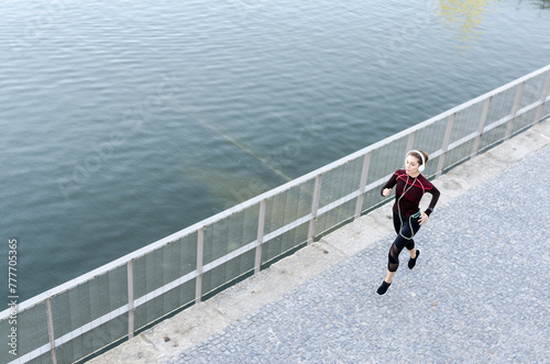 up view of a woman running and jogging in a park with lake and listening music