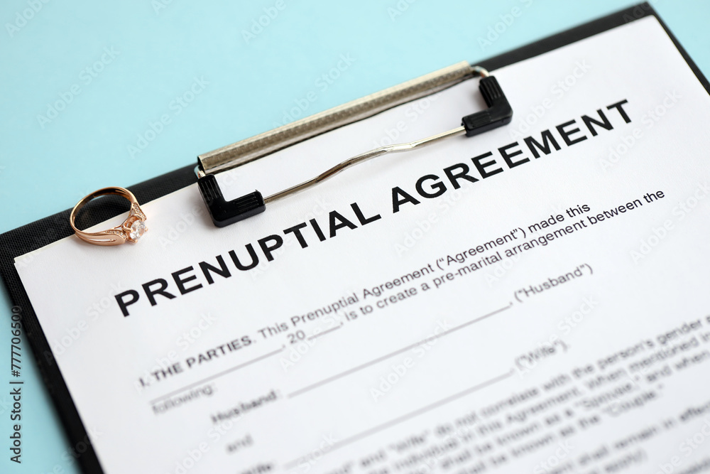 Prenuptial agreement and wedding ring on table. Premarital paperwork process close up