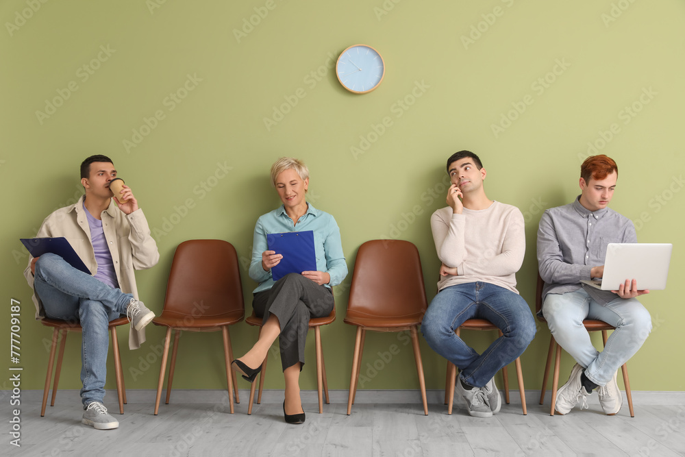 Applicants waiting for job interview near green wall in room Applicants waiting for job interview near green wall in room