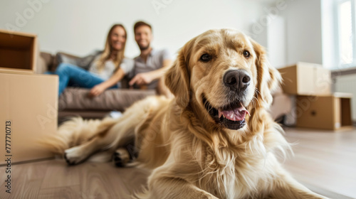 A happy golden retriever lying on the floor with a couple sitting in the background of a new home