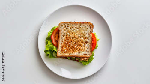 An open-faced sandwich with lettuce and tomato on a white plate viewed from above