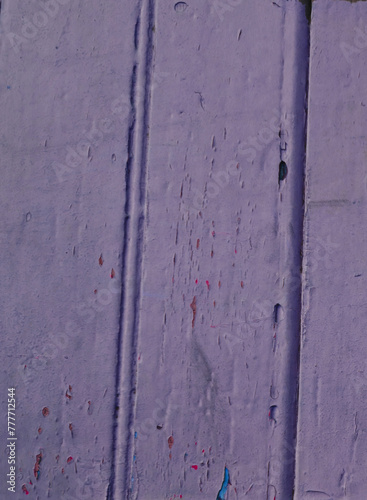 Old textured surface painted with purple peeling paint.