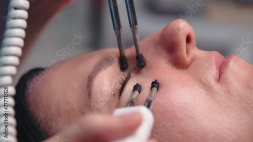 A middle-aged woman undergoes electrotherapeutic facial rejuvenation procedures in a cosmetologist's office. photo