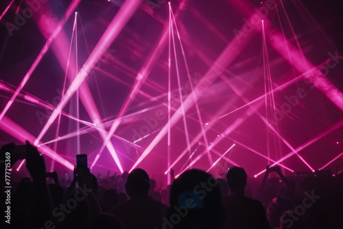 Silhouetted spectators enjoying an intense light show during a live concert with dynamic beams and fog