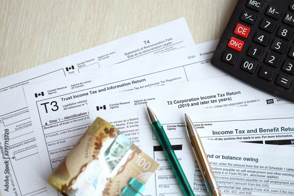 Obraz premium Many blank Canadian tax forms lies on table with canadian money bills, calculator and pen close up. Taxation and annual accountant paperwork in Canada