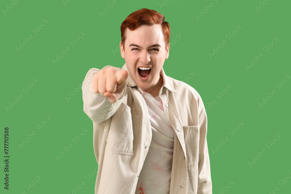 Angry young man pointing at viewer on green background. Accusation concept Angry young man pointing at viewer on green background. Accusation concept