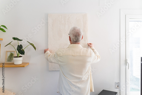 Man Hanging Painting On Wall photo