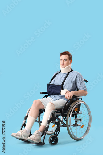 Injured young man after accident in wheelchair on blue background