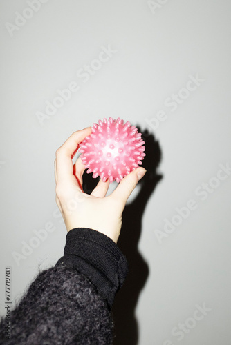 Hand holding a neon pink sport spike ball with hard direct flashlight photo