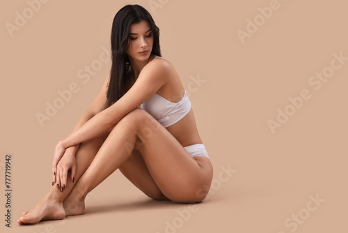 Pretty young woman in white underwear sitting on brown background