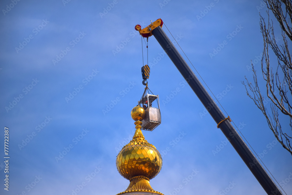Fototapeta premium Renovation, restoration, refurbishment. Unrecognizable worker renovating wall of classical style building, standing on scaffolding. Construction worker prepares house facade wall for