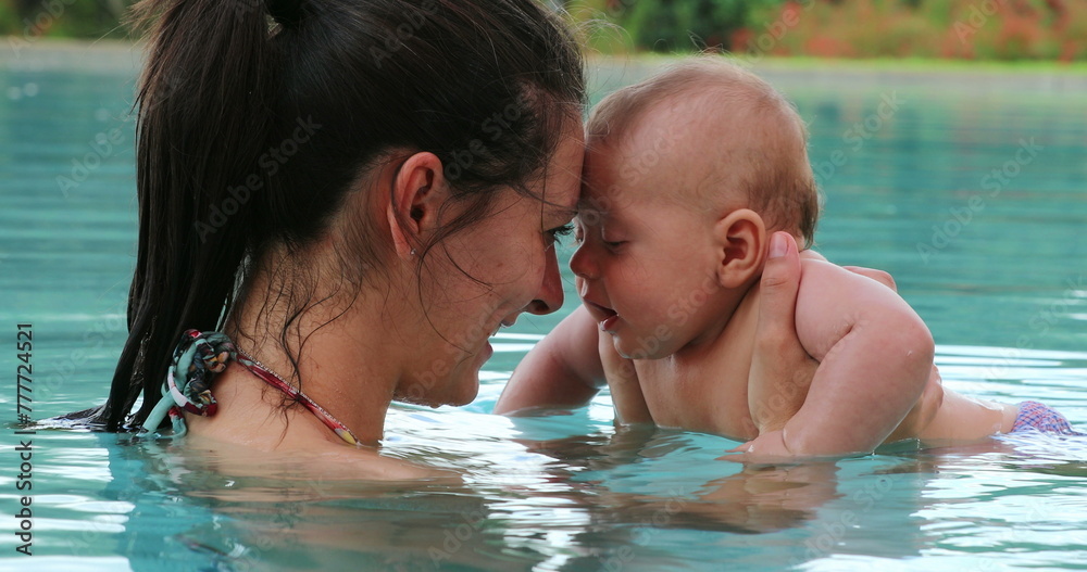 Mother and baby interaction at the swimming pool water showing love and affection smiling Mother and baby interaction at the swimming pool water showing love and affection smiling