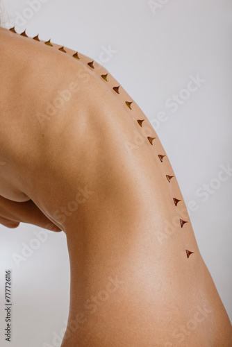 Close up photo of naked woman's skin of the back with thorns on spine photo