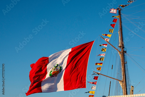 A large flag of Peru flying on the mast of a ship.
