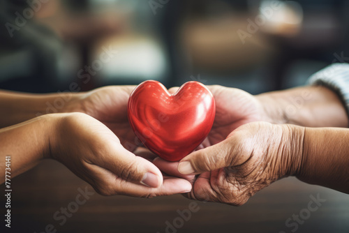 Young and old people hands holding red heart together. Love, help, social responsibility, donation, charity, ecology, gratitude, appreciate, world heart day concept photo