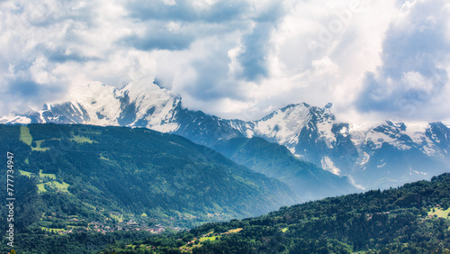 Mont-Blanc massif, covered by stormy clouds, as viewed from the A40 highway, in France. The town of Saint-Gervais-les-Bains is visible in the valley ahead.