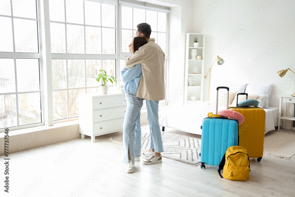 Young couple of tourists with bags hugging in hotel room Young couple of tourists with bags hugging in hotel room