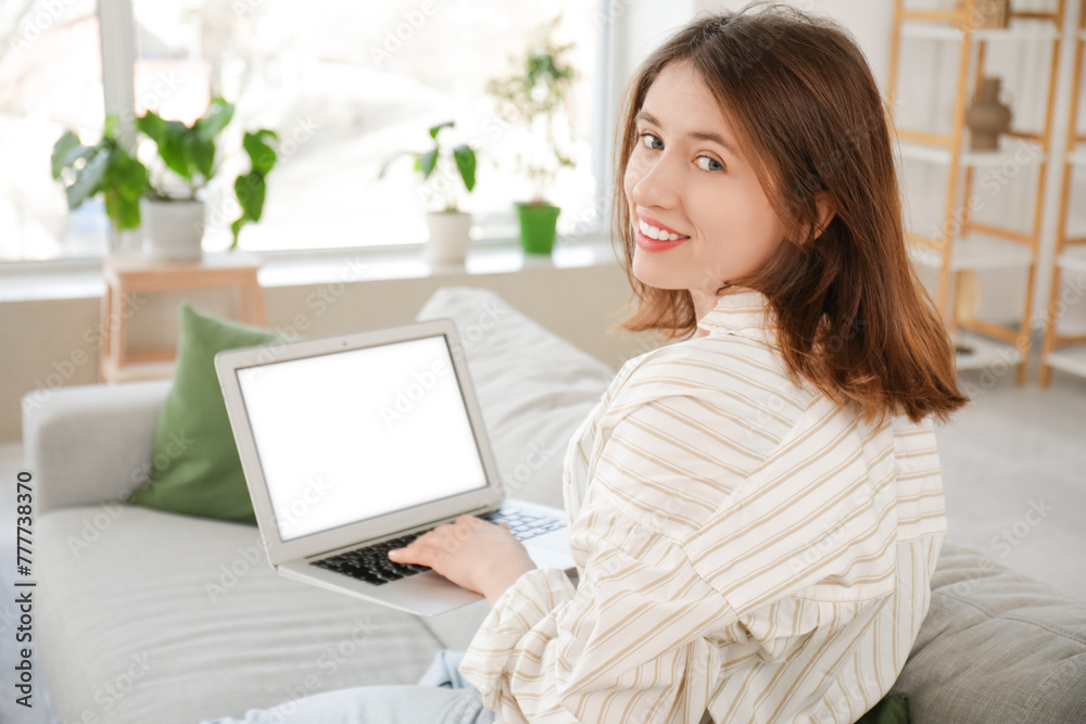 Beautiful young woman resting on sofa and using laptop in living room Beautiful young woman resting on sofa and using laptop in living room