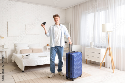 Male tourist with photo camera and suitcase in hotel room