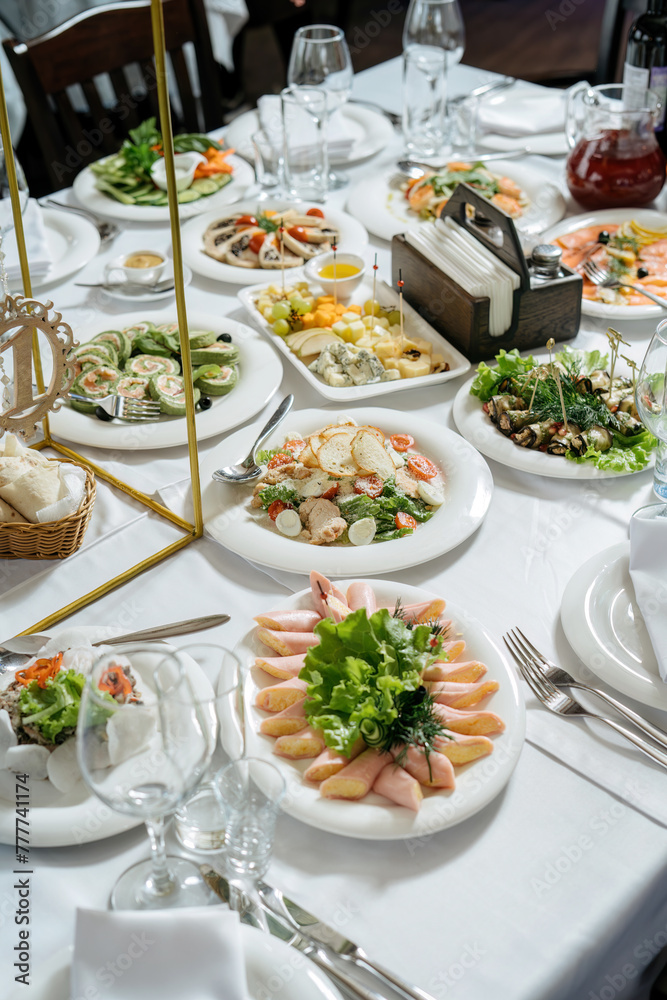 Scene of a table with appetizers. On white wooden background. Board with appetizers, meat with capers, cheese, assorted holiday dishes. Olives, Italian bread.