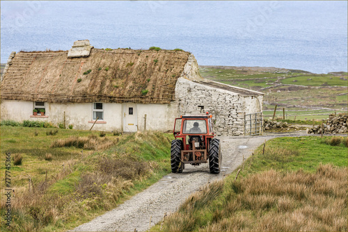 Traditional old irish house with a male on a tractor