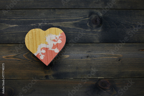 wooden heart with national flag of bhutan on the wooden background.