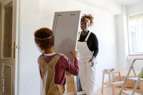 Kid helping his mother moving boxes in new home photo
